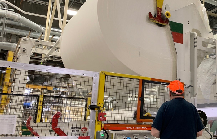 A man standing with a giant roll of tissue